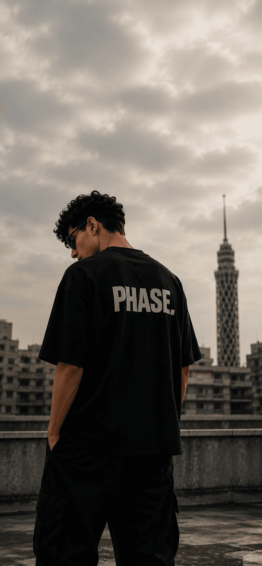 Model wearing a PHASE black t-shirt on a Cairo rooftop